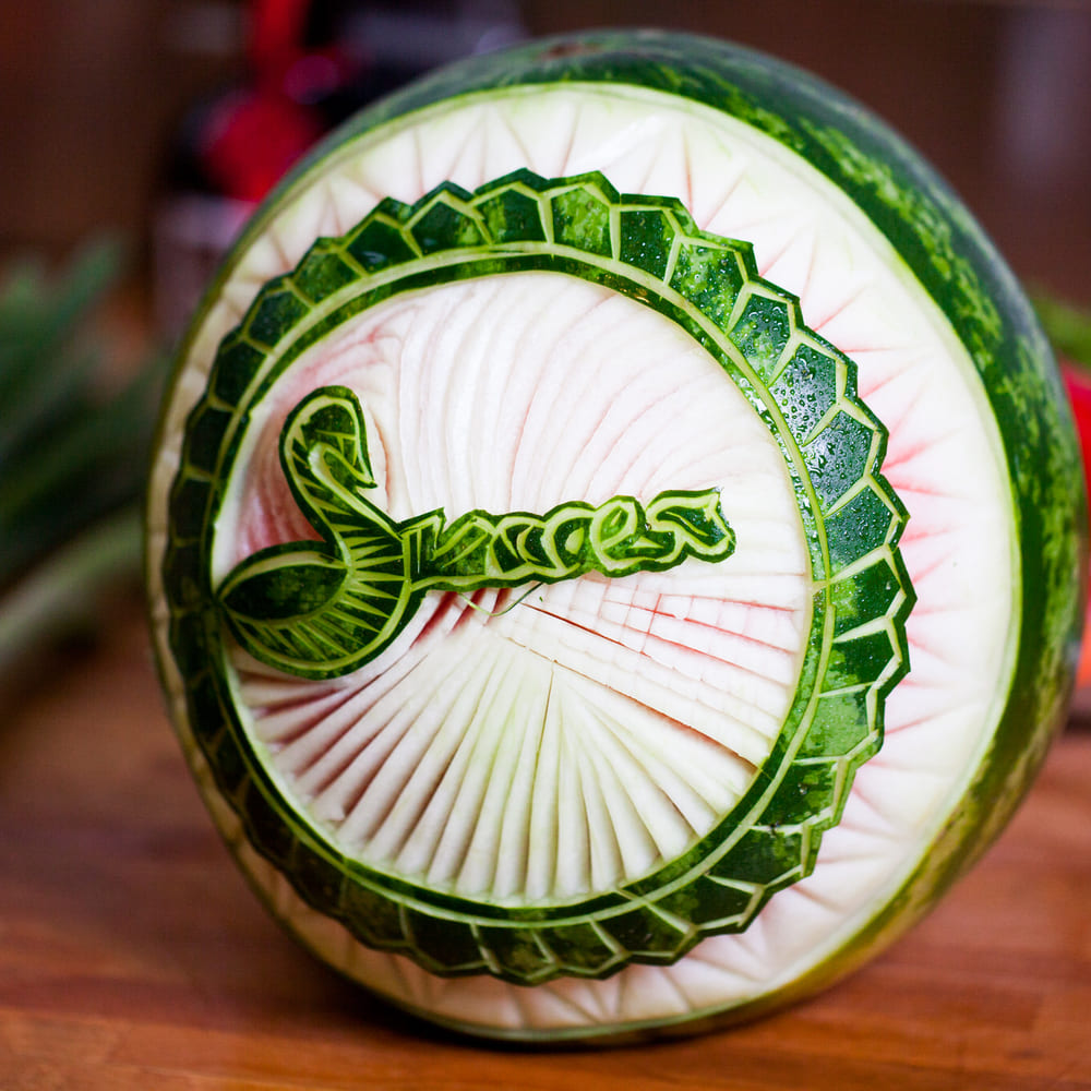 The Success swan logo carved into the rind of a watermelon on a wooden kitchen bench.